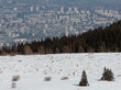 Blick von einem schneebedecktem Hügel auf eine Stadt.