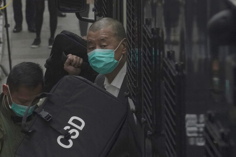 Jimmy Lai steigt aus einem Fahrzeug aus und wird von Menschen mit Taschen vor Blicken geschützt.