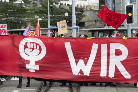 Demonstration mit einem roten Banner, auf dem ein Venussymbol zu sehen ist.