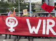 Demonstration mit einem roten Banner, auf dem ein Venussymbol zu sehen ist.