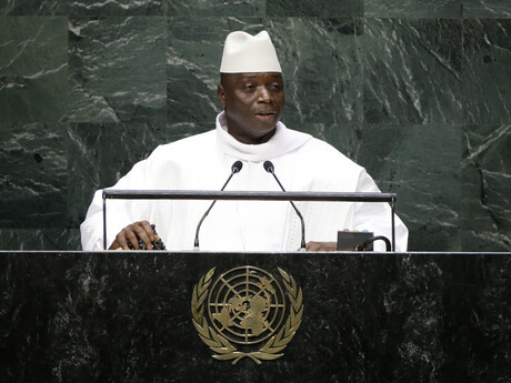 Ein Mann in weißer Kleidung steht an einem Rednerpult.