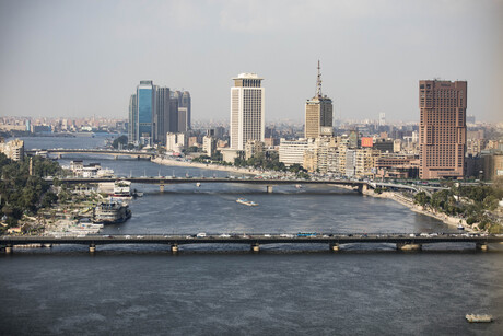 Am Flussufer des Nil sind zahlreiche Häuser und Hochhäuser zu sehen; drei Brücken reichen über den Fluss