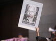 Eine Hand hält ein Plakat mit dem Gesicht von Julian Assange hoch. Auf dem Plakat steht: "Free Assange. No U.S. Extradition."