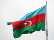 Die Nationalflagge Aserbaidschans (erst ein hellblauer, dann ein roter und zuletzt ein dunkelgrüner Querbalken; auf dem roten Balken sind außerdem ein Halbmond und ein Stern abgebildet) weht vor einem wolkenverhangenen Himmel