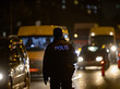 Ein türkischer Polizist steht mit dem Rücken zur Kamera und blickt einigen Autos auf einer Straßen entgegen; es ist Abend, der Polizist trägt eine dunkle Uniform und die Autos haben ihre Lichter angeschaltet