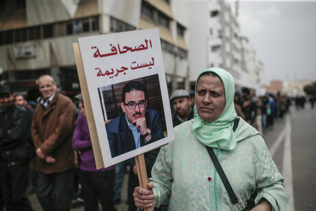 Eine Frau in Marokko trägt ein Schild mit dem Bild von Taoufik Bouachrine und der Aufschricht "Journalismus ist kein Verbrechen".