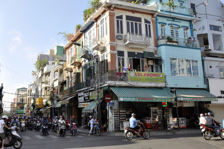 Straßenecke mit Läden und Personen auf Rollern in Ho-Chi-Minh-Stadt