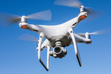 Eine weiße Drohne mit vier Propellern und Überwachungskamera.