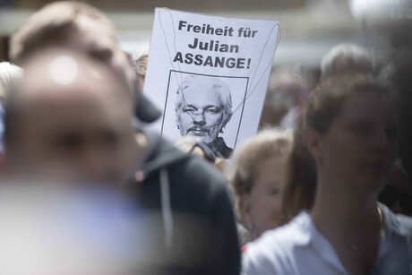 Auf einer Demonstration in Aachen fordern Demonstrierende Freiheit für Julian Assange, dazu hält eine Person ein Schild mit diesem Spruch und einem Foto von Assange.
