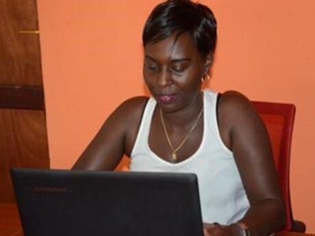 Christine Kamikazi sitzt vor einem Laptop und arbeitet