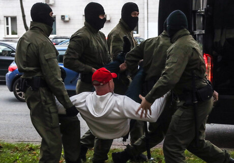 Ein Demonstrant wird von vier nicht ausgewiesenen Sicherheitskräften in einen Minivan getragen 