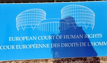 Der Schatten einer Frau fällt auf ein Schild vor dem Gebäude des Europäischen Gerichtshofs für Menschenrechte (EGMR) in Straßburg. 