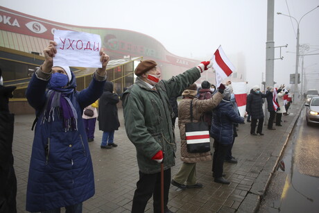 Mehrere Menschen stehen mit rot-weißen Flaggen am Straßenrand.