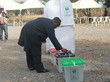 Mann wirft Zettel in Wahlurne.