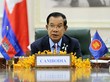 Premierminister Hun Sen hält im sitzen eine Anpsrache; vor ihm auf dem Tisch ist ein Schild mit der Aufschrift "Cambodia" und zwei kleine Flaggen aufgestellt