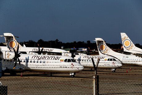 Mehrere weiße Flugzeuge stehen auf einem eingezäunten Flugplatz