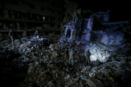 Das Foto zeigt die Trümmer eines Hauses, auf denen uniformierte Mitglieder der Gendarmerie stehen und mit Scheinwerfern und Taschenlampen in die Dunkelheit leuchten.