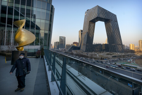 Ein Mann geht über eine Aussichtsplattform, von der aus man das graue, torartige Hauptgebäude von CCTV und CGTN sehen kann