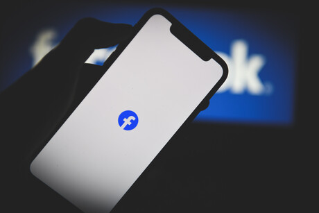 Handybildschirm mit facebook-Logo. Im Hintergrund auch das facebook-Logo
