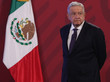 Der Präsident steht mit ernstem Blick neben der mexikanischen Nationalflagge