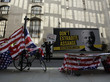 Protest für die Freilassung von Julian Assange mit zerrissenen USA-Flaggen, einem Schild mit der Aufschrift "Stop this political trial" und einem anderen Schild mit der Aufschrift "Don't extradite Assange"