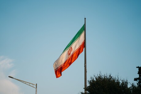 Eine Flagge mit je einem grünen, weißen und rotem Querstreifen und einem rotem Emblem in der Mitte.