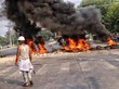 Ein Mann steht auf einer Straße vor brennenden Gegenständen.