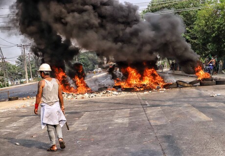 Ein Mann steht auf einer Straße vor brennenden Gegenständen.