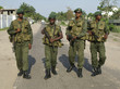 Vier bewaffnete Soldaten gehen eine Straße entlang