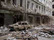 Der Krieg in der Ukraine hinterlässt immense Zerstörung und gefährdet insbesondere Medienschaffende. Zu sehen ist ein zerstörter Wohnkomplex und ein staubbedecktes Auto im Bildmittelpunkt. © picture alliance  EPA  SERGEY KOZLOV