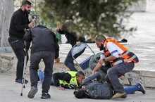 Rettungskräfte des Palästinensischen Roten Kreuzes versorgen einen verletzten Journalisten, der am Boden liegt.