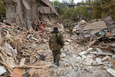 Zwei Personen laufen durch die Trümmer zerstörte Häuser in Stepanakert in Bergkarabach. 