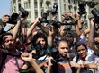 Medienschaffende halten bei einer Demonstration Kameras ihre Kameras in die Luft.