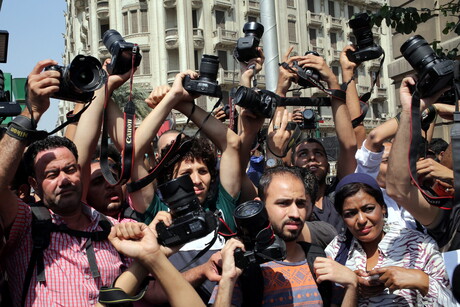 Medienschaffende halten bei einer Demonstration Kameras ihre Kameras in die Luft.