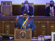 Nicolás Maduro steht in Uniform an einem Rednerpult; hinter ihm sitzen zwei Männer und klatschen
