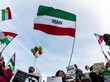 Straßenprotest im Iran, mit Flaggen und Plakaten.