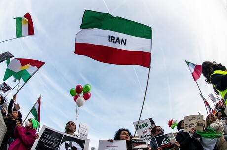 Straßenprotest im Iran, mit Flaggen und Plakaten.