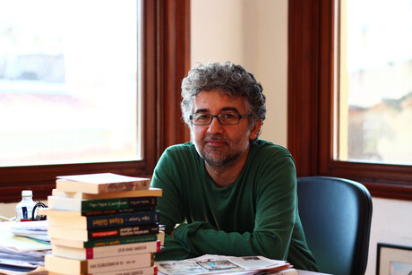 Erol Önderoglu sitzt an einem Schreibtisch hinter einem Stapel Bücher