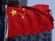 Die chinesische Flagge (roter Grund mit fünf gelben Sternen in der linken oberen Ecke) weht vor einem Hochhaus