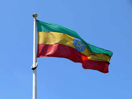 Äthiopische Flagge: dunkelgrüner, gelber und roter Querbalken. Darauf wurde mittig ein gelber Stern in einem blauen Kreis platziert