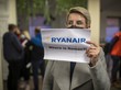 Frau hält einen Schild mit der Aufschrift "Ryanair, where is Roman?!" hoch