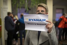 Frau hält einen Schild mit der Aufschrift "Ryanair, where is Roman?!" hoch