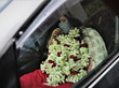 Zu sehen ist Rozina Islam in einem Auto nach ihrer Verhaftung. Auffällig ist ein großer Blumenschmuck, der ihr um den hals gehängt wurde.