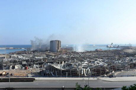 Nach der Explosion im Hafen von Beirut sind nur noch die Überreste von Häusern zu sehen; grauer Qualm steigt in den blauen Himmel auf