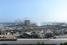 Nach der Explosion im Hafen von Beirut sind nur noch die Überreste von Häusern zu sehen; grauer Qualm steigt in den blauen Himmel auf
