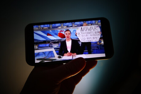Auf einem Handydisplay ist die russische Journalistin Marina Owsjannikowa zu sehen, die eine Sendung moderiert.